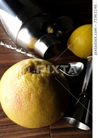 Make a cocktail with a shaker using grapefruit and lemon 71963146