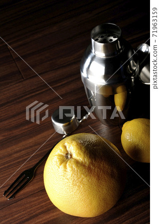 Make a cocktail with a shaker using grapefruit and lemon Make a cocktail with a shaker using grapefruit and lemon 71963159