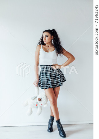 Portrait of a beautiful fashionable brunette woman in a skirt with a bear toy Portrait of a beautiful fashionable brunette woman in a skirt with a bear toy 71963245