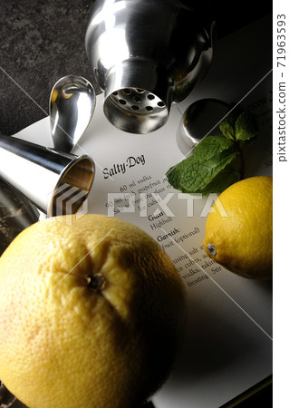 Make a cocktail with a shaker while looking at a cocktail book using grapefruit, lemon and mint Make a cocktail with a shaker while looking at a cocktail book using grapefruit, lemon and mint 71963593