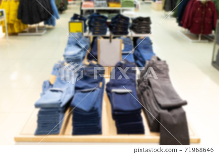 clothing store with a large assortment of pants and jeans hanging on hanger, blurred and defocused 71968646
