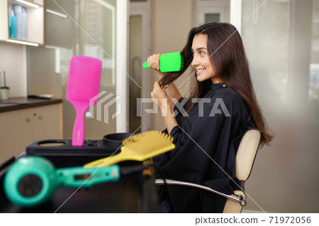 Female customer combs hair in hairdressing salon Female customer combs hair in hairdressing salon 71972056