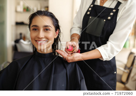 Hairdresser applies mousse on woman's hair 71972060