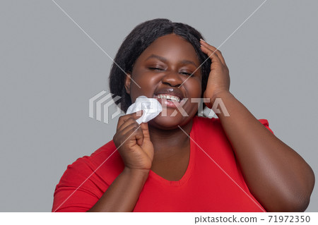 Young dark-skinned woman holding sponge for face cleansing 71972350