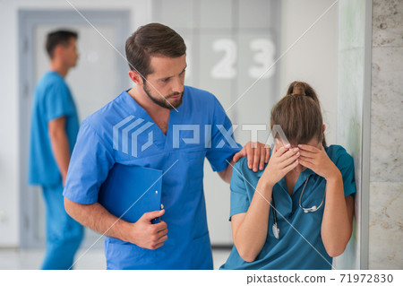 Female doctor feeling happy while her male colleague supporting her Female doctor feeling happy while her male colleague supporting her 71972830