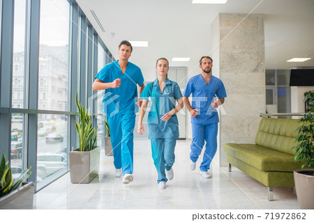 Three doctors running through the hospital corridor being in a hurry 71972862