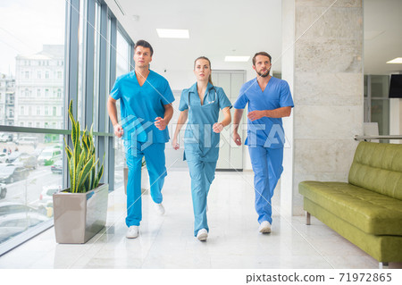 Three doctors running throtugh the hospital corridor being in a hurry Three doctors running throtugh the hospital corridor being in a hurry 71972865