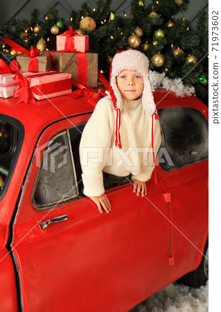 Boy on the background of a red car with gifts. 71973602