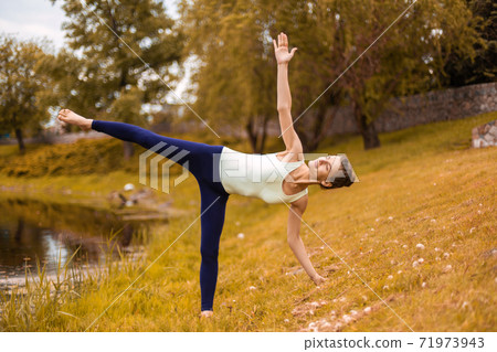 Young attractive yogi woman practicing yoga, doing Utthita Trikonasana exercise, extended triangle pose 71973943