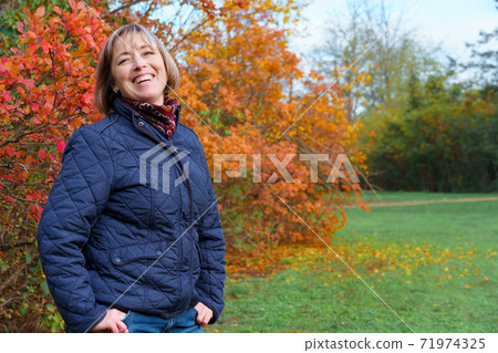 portrait of a woman posing in autumn park, bright colorful leaves as background portrait of a woman posing in autumn park, bright colorful leaves as background 71974325