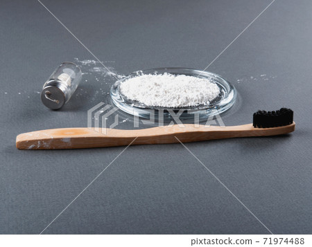A bamboo toothbrush with a floss in a glass and toothpowder. 71974488