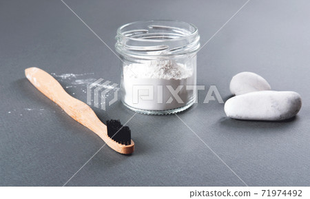 The bamboo toothbrush with toothpowder and two stones on the grey background. The bamboo toothbrush with toothpowder and two stones on the grey background. 71974492