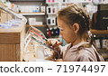 Little child girl using new smartphone on counter in an electronics store. 71974497