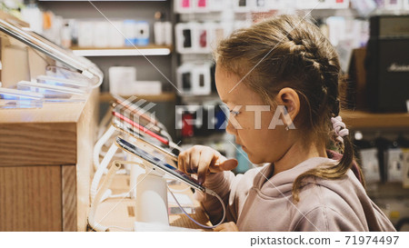 Little child girl using new smartphone on counter in an electronics store. Little child girl using new smartphone on counter in an electronics store. 71974497