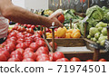 Close-up hands of grocery worker is arranging vegetables on store shelves 71974501