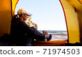 Woman is puts her shoes while sits in camping tent at beautiful beach 71974503