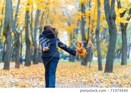 a girl running through the park and enjoys autumn, beautiful nature with yellow leaves 71974840