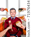 Junk food. Diverse fast food. The guy on the couch. In front of a man hands with sushi, pizza and burger. 71976434