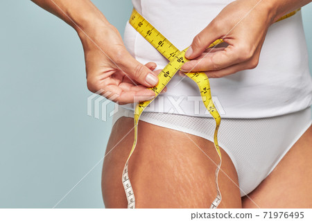 Woman measuring her waist with a tape measure 71976495