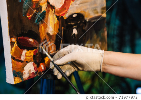 Artist paints a picture of oil paint brush in hand with palette close up. Artist paints a picture of oil paint brush in hand with palette close up. 71977972