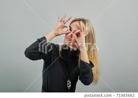 Making glasses of fingers, looking at camera smiling, funny, hold hands eyes Making glasses of fingers, looking at camera smiling, funny, hold hands eyes 71985662
