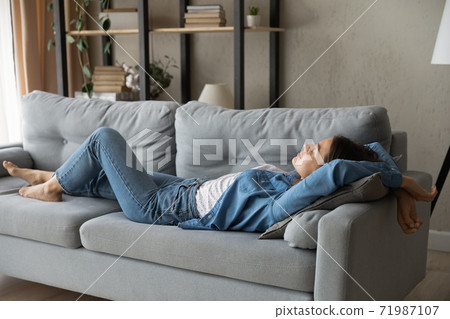 Exhausted woman relax on sofa at home daydreaming Exhausted woman relax on sofa at home daydreaming 71987107