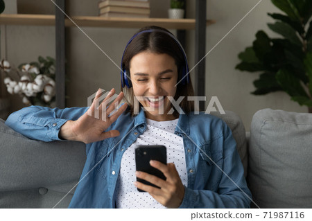 Smiling woman in headphones have video call on smartphone 71987116