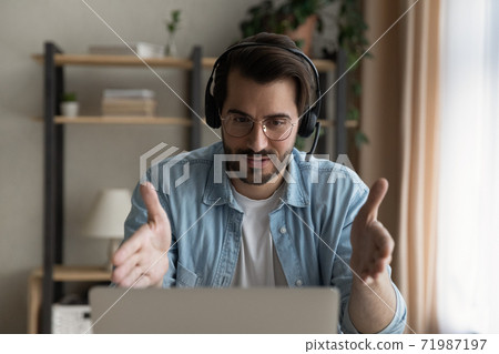 Caucasian man in headphones talk on video call on laptop 71987197