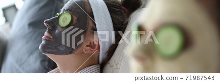 People are lying on couch with cosmetic mask faces People are lying on couch with cosmetic mask faces 71987543