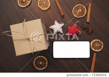 flat lay with smarthone and christmas decorations on walnut table 71988958