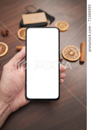 Man hand hold smarthone with white screen with christmas decorations on background 71988995