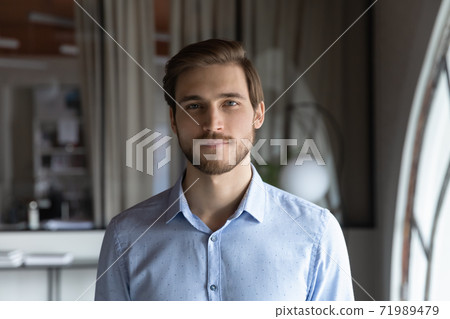 Headshot portrait of confident millennial businessman standing in modern office 71989479