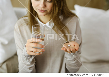 Close-up woman holding pills time to take medications, cure for headache, high blood pressure or cholesterol level remedy pain killer drugs. Stay at home concept during Coronavirus pandemic and self Close-up woman holding pills time to take medications, cure for headache, high blood pressure or cholesterol level remedy pain killer drugs. Stay at home concept during Coronavirus pandemic and self 71990439