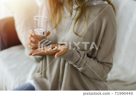 Close-up woman holding pills time to take medications, cure for headache. Medicine concept during self isolation and Coronavirus pandemic 71990449