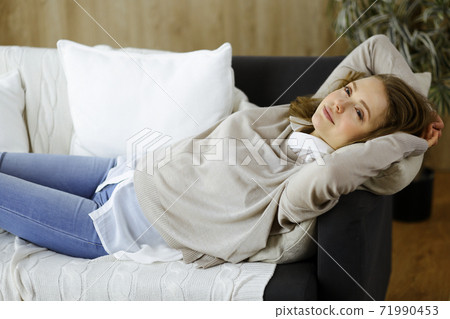 Happy brunette woman put hands behind head lying leaned on couch european female enjoy lazy weekend or vacation in cozy living room, housewife relaxing feels satisfied accomplish chores housework 71990453