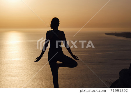 The woman with yoga posture on the mountain at sunset 71991892