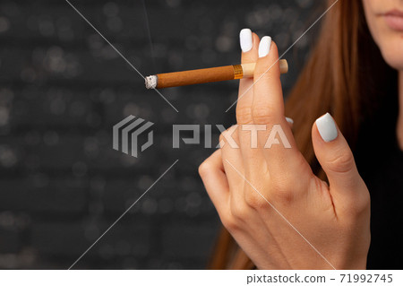 Female hand holding lighted cigarette close up - Stock Photo [71992745]