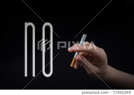 Hand is holding a cigarette on black background Hand is holding a cigarette on black background 71992849
