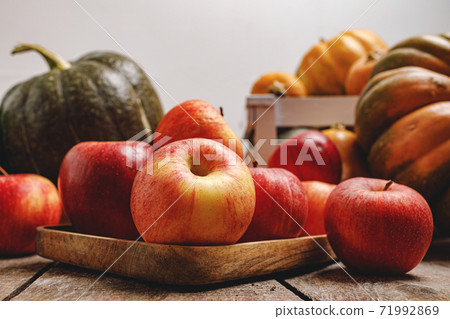 Pumpkins and red apples on wooden background Pumpkins and red apples on wooden background 71992869