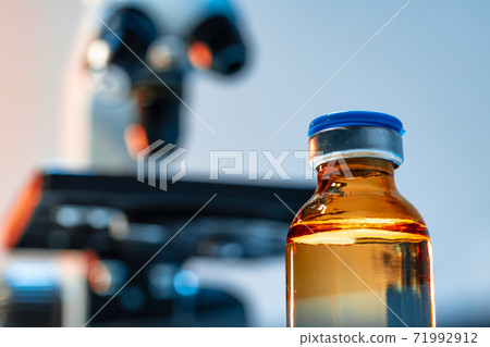 Medical vial with medication near microscope photo 71992912