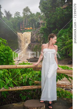 Beautiful woman posing against the background of muddy waters of Tegenungan waterfall 71994370