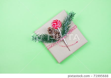 Christmas gift box wrapped in brown craft paper with corn, fir-tree and candy on green background.New Year and Christmas concept. 71995688