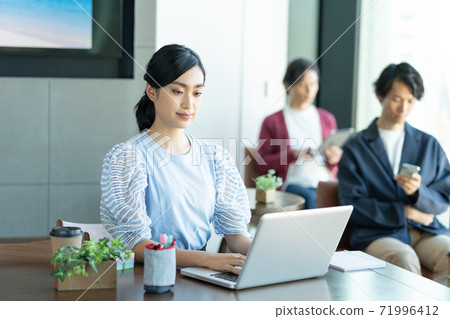 A young woman working on a computer in a coworking space 71996412