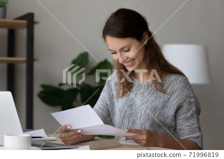 Happy millennial woman reading paper correspondence letter. 71996819