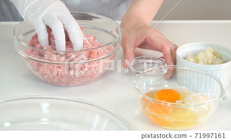 Housewife cooking scene where minced meat is mixed with salt and pepper and kneaded Housewife cooking scene where minced meat is mixed with salt and pepper and kneaded 71997161