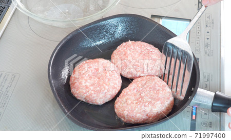 Cooking scene where hamburger is cooked in a frying pan 71997400