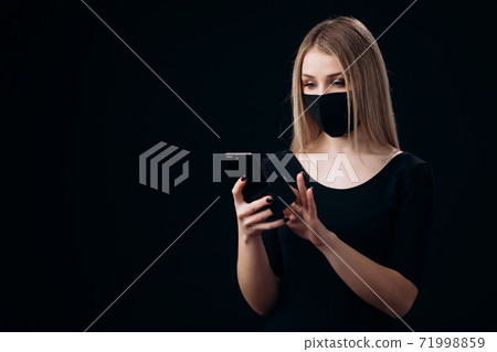 Woman in mask holding credit card and smartphone 71998859