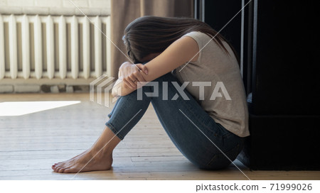 Frustrated unhappy young woman embracing knees, sitting on floor 71999026