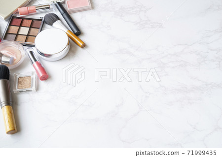 A bird's-eye view of a set of makeup tools placed on a marble plate 71999435