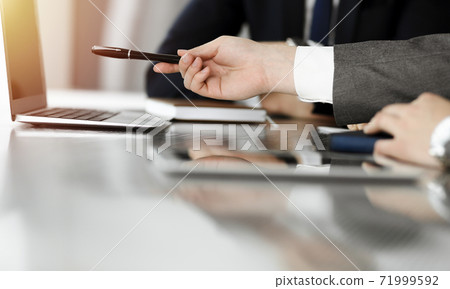 Unknown businessmen and woman sitting, using laptop computer and discussing questions at meeting in sunny office, close-up. Success concept 71999592